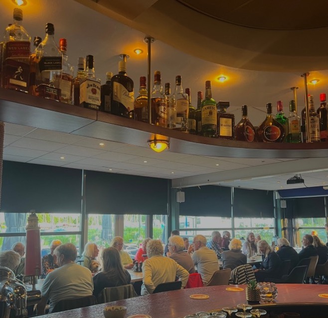 De bar met een volle plank sterke drank en een vol café