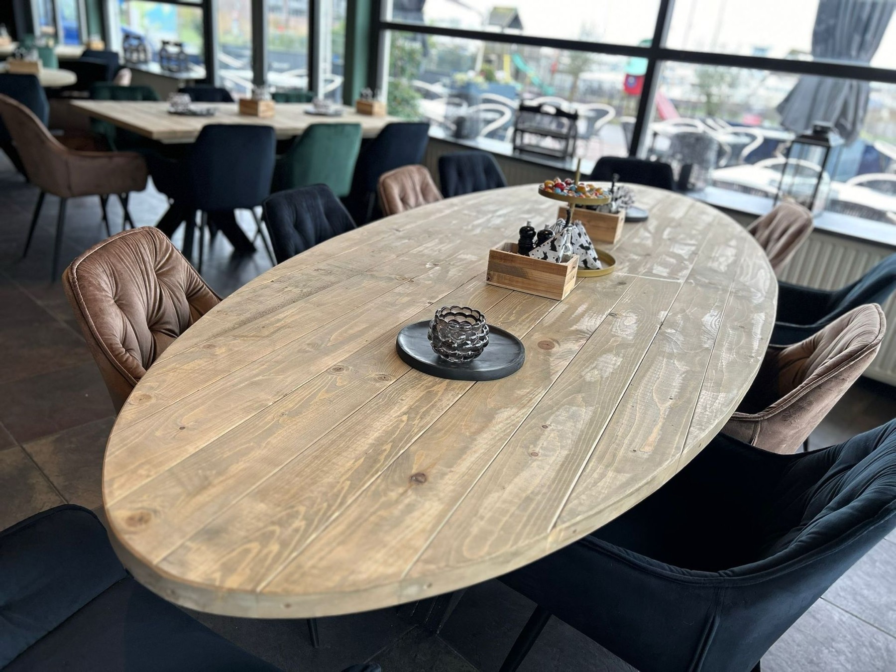 Het interieur van 't Haventje met houten tafels, velours stoelen en uitzicht op de haven